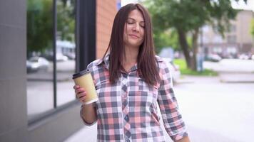 mooi meisje gaat na boodschappen doen met pakketjes en houdt een glas met koffie in haar hand. langzaam beweging. video