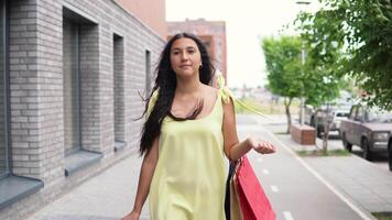 Beautiful Young Girl in a long dress goes around the city after shopping having a good mood. 4K video