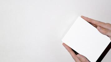 Male hands holding white box mock up, top view. White background, top view, copy space photo
