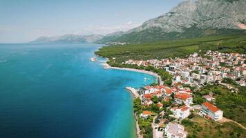 vibrerande Bayside stad på kroatisk kust. antenn se av livliga stad bredvid de klar turkos hav vattnen. makarska riviera stad. video