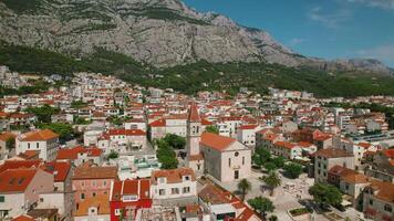 expansif Urbain vue avec église surplombant le croate Makarska côte d'azur. côtier ville contre une montagneux horizon. video