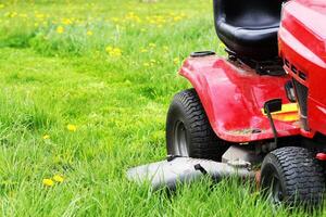 Gardener driving a riding lawn mower in a garden . Cutting grass photo