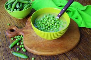 Fresh green pea soup with pea seeds and pea pods around . Selective Focus, Focus on the pea in the middle of the soup photo