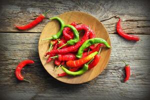 Wooden bowl with red, chilli pepers on rustic dark background. photo