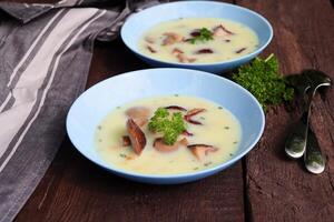 Creamy soup with porcini mushroom and herbs on wooden table photo