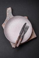 Cutlery fork, knife and spoon on a dark textured concrete background photo