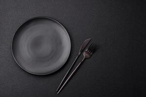 Cutlery fork, knife and spoon on a dark textured concrete background photo