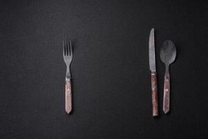 Cutlery fork, knife and spoon on a dark textured concrete background photo