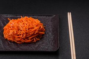 Tasty spicy Korean carrot with spices and herbs on a dark concrete background photo