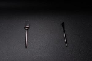cuchillería tenedor, cuchillo y cuchara en un oscuro texturizado hormigón antecedentes foto