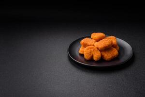 Delicious fresh crispy chicken nuggets on a dark concrete background photo