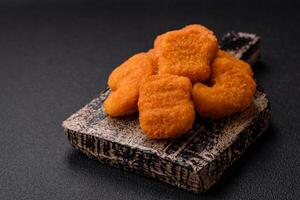 Delicious fresh crispy chicken nuggets on a dark concrete background photo