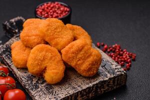 deliciosos nuggets de pollo crujientes y frescos sobre un fondo de hormigón oscuro foto