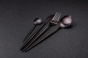 Cutlery fork, knife and spoon on a dark textured concrete background photo