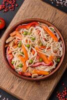 Delicious rice noodles or udon with chicken, carrots, pepper, salt, spices and herbs photo