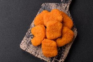 Delicious fresh crispy chicken nuggets on a dark concrete background photo