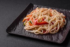 Delicious rice noodles or udon with chicken, carrots, pepper, salt, spices and herbs photo