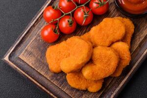 Delicious fresh crispy chicken nuggets on a dark concrete background photo