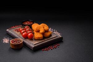 Delicious fresh crispy chicken nuggets on a dark concrete background photo