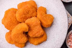 Delicious fresh crispy chicken nuggets on a dark concrete background photo