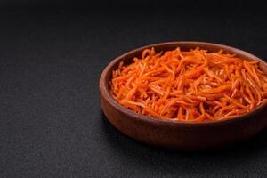 Tasty spicy Korean carrot with spices and herbs on a dark concrete background photo