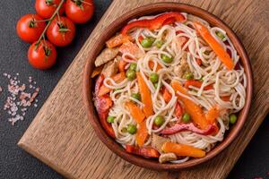 Delicious rice noodles or udon with chicken, carrots, pepper, salt, spices and herbs photo