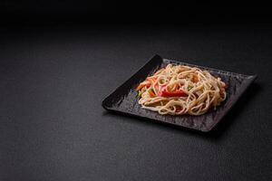 Delicious rice noodles or udon with chicken, carrots, pepper, salt, spices and herbs photo