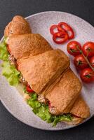 Delicious fresh crispy croissant with chicken or beef meat, lettuce, tomatoes, spices and sauce photo