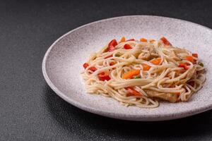 Delicious rice noodles or udon with chicken, carrots, pepper, salt, spices and herbs photo