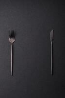 Cutlery fork, knife and spoon on a dark textured concrete background photo