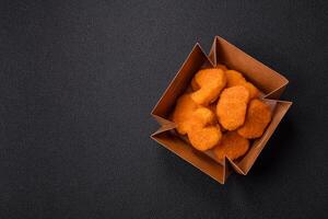 Delicious fresh crispy chicken nuggets on a dark concrete background photo