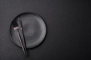 Cutlery fork, knife and spoon on a dark textured concrete background photo