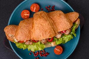 Delicious fresh crispy croissant with chicken or beef meat, lettuce, tomatoes, spices and sauce photo