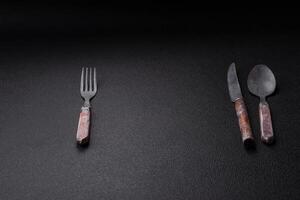 Cutlery fork, knife and spoon on a dark textured concrete background photo