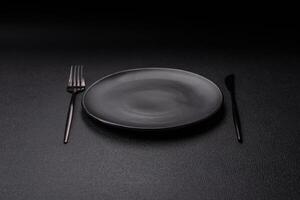 Cutlery fork, knife and spoon on a dark textured concrete background photo