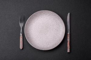 Cutlery fork, knife and spoon on a dark textured concrete background photo