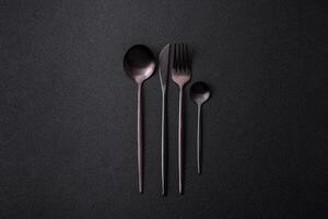 Cutlery fork, knife and spoon on a dark textured concrete background photo