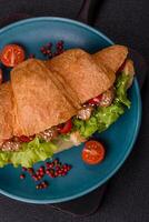 Delicious fresh crispy croissant with chicken or beef meat, lettuce, tomatoes, spices and sauce photo