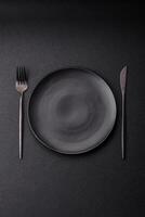 Cutlery fork, knife and spoon on a dark textured concrete background photo