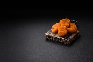 Delicious fresh crispy chicken nuggets on a dark concrete background photo