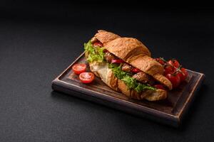 Delicious fresh crispy croissant with chicken or beef meat, lettuce, tomatoes, spices and sauce photo