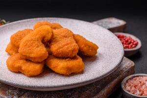 Delicious fresh crispy chicken nuggets on a dark concrete background photo