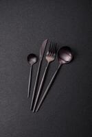 Cutlery fork, knife and spoon on a dark textured concrete background photo