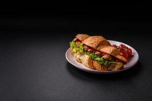 Delicious fresh crispy croissant with chicken or beef meat, lettuce, tomatoes, spices and sauce photo