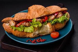 Delicious fresh crispy croissant with chicken or beef meat, lettuce, tomatoes, spices and sauce photo