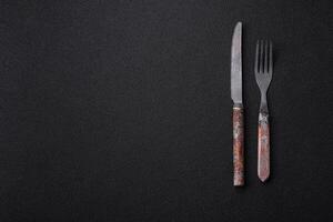 Cutlery fork, knife and spoon on a dark textured concrete background photo