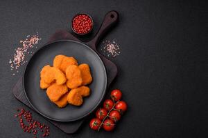 Delicious fresh crispy chicken nuggets on a dark concrete background photo