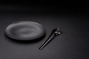 Cutlery fork, knife and spoon on a dark textured concrete background photo