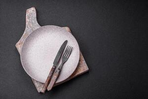 Cutlery fork, knife and spoon on a dark textured concrete background photo