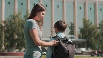 en ligne éducation, retour à école, content écolier, apprendre cours. une femme met un Pomme dans une d'écolier sac à dos et envoie il à école. écolier court à école video